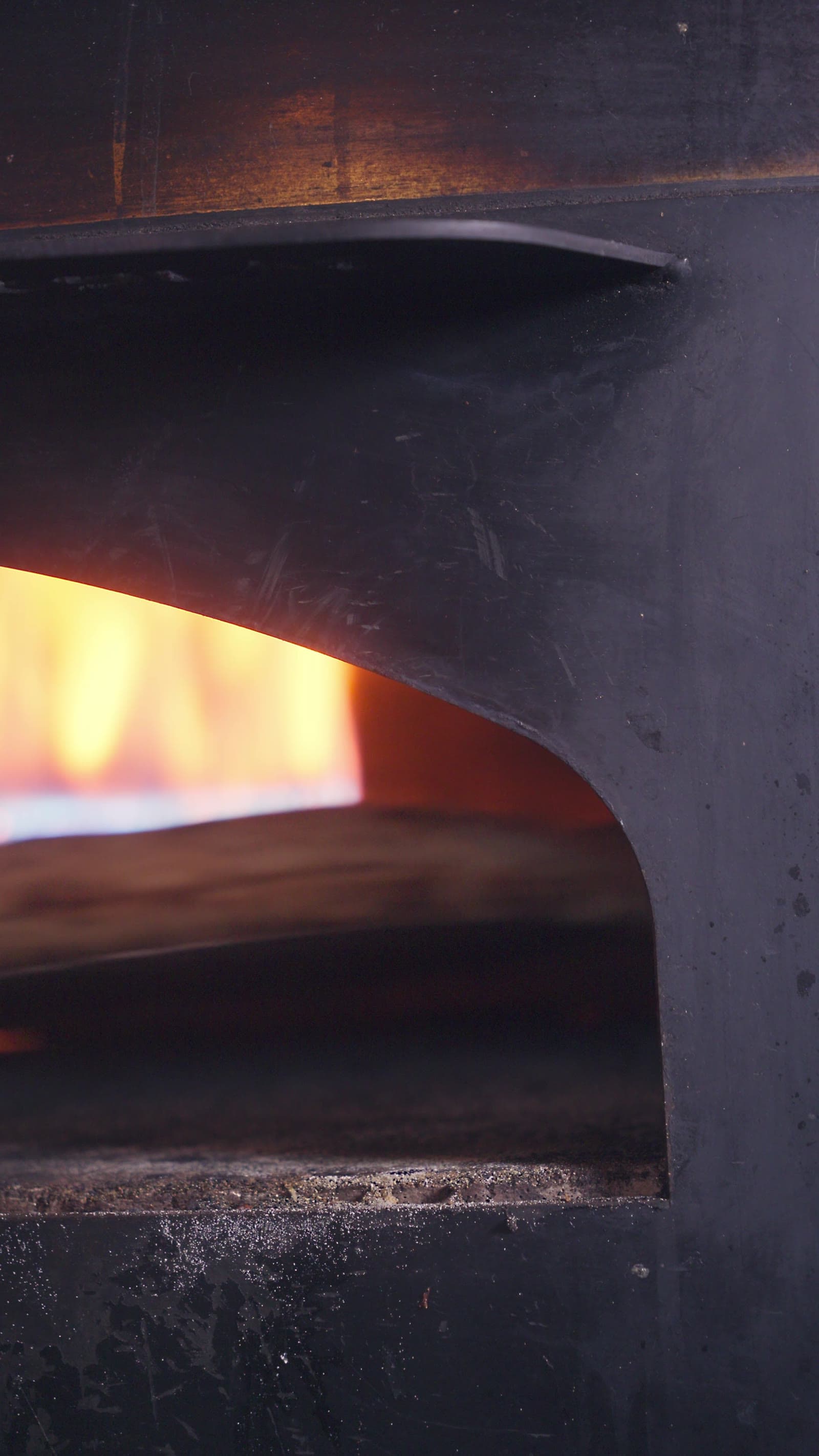 Frame from the El Pirata film: the mouth of a wood-fired oven, flame behind blackened steel.