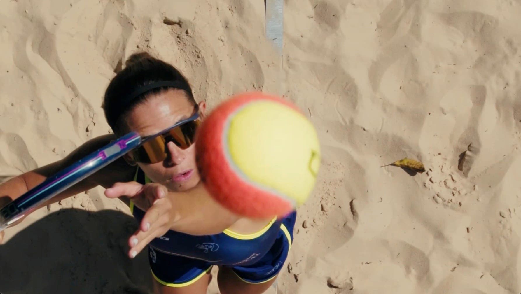 Still from the Giói shoot: an athlete setting up to strike the ball on the sand court.