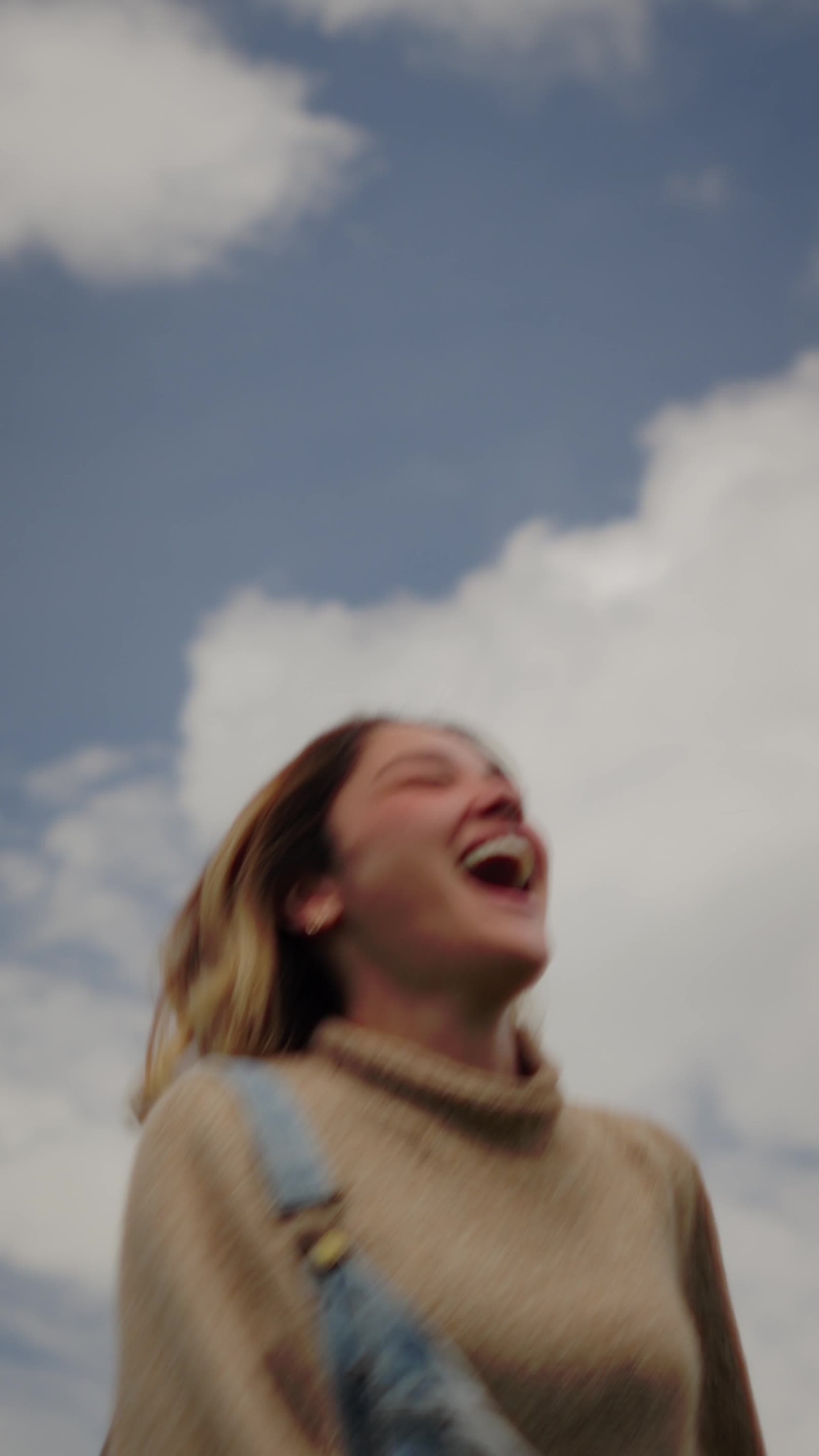 Frame from the Munay film: a guest laughing, head back against a clouded sky.